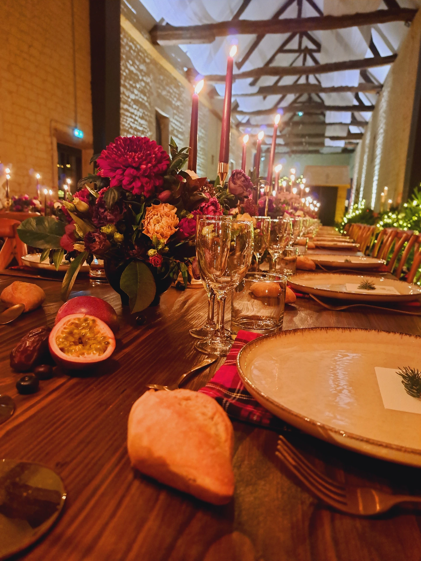 Décoration de table avec chandelles et fleurs bordeaux créant une ambiance dîner mariage chaleureuse et immersive.