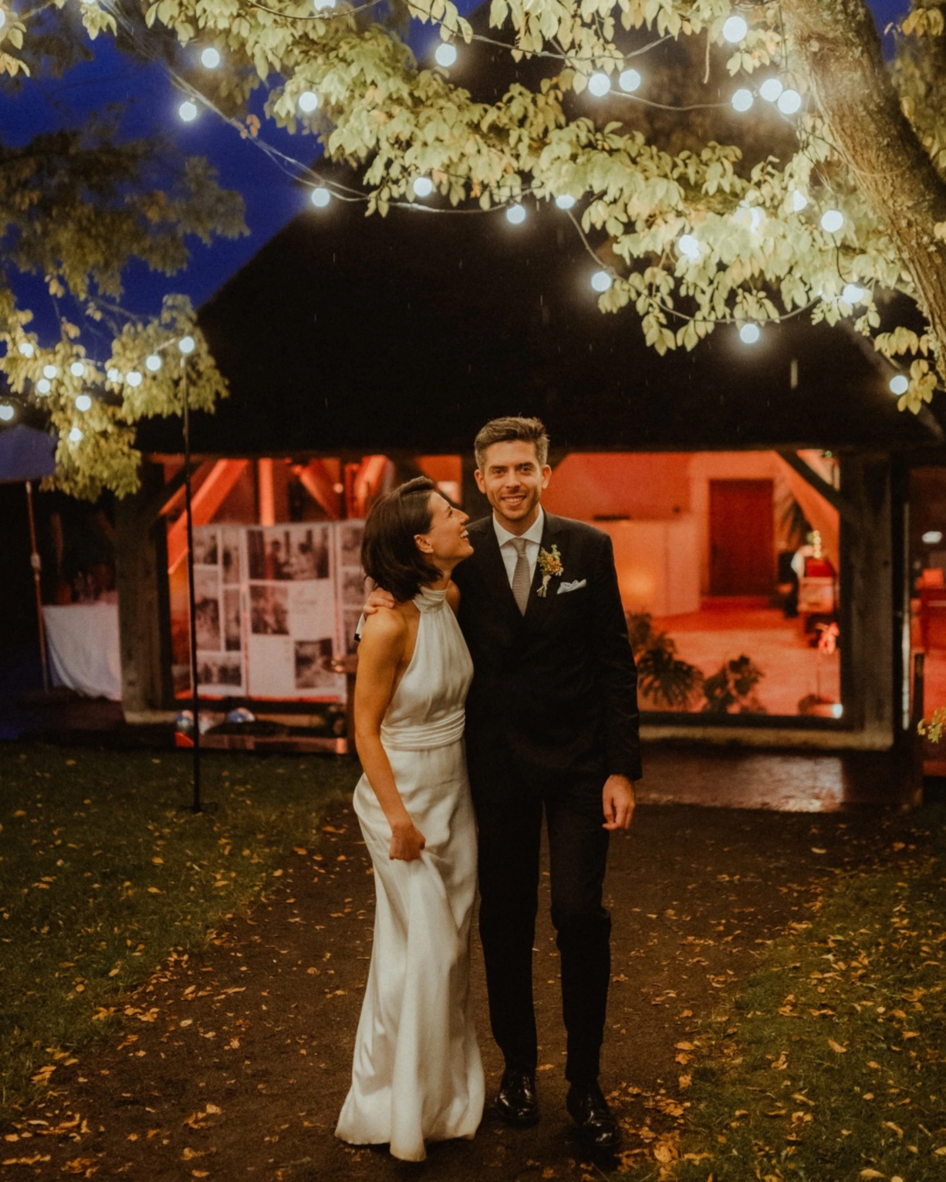 Un couple sous des guirlandes lumineuses lors d’un mariage au Val Gaudry en Normandie, illustrant l’importance de la lumière mariage pour créer une ambiance chaleureuse et réussie. Photo Nemo Wallinka.