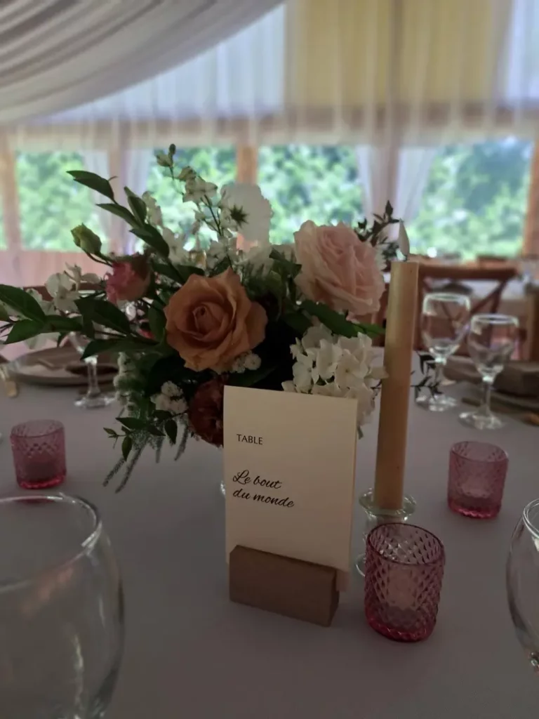 Table ronde dressée avec fleurs, vaisselle et décoration de mariage