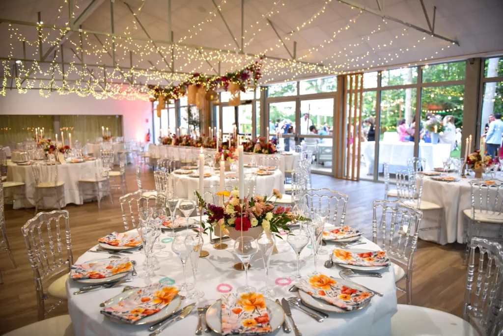Salle décorée avec guirlandes lumineuses et tables rondes fleuries créant une ambiance dîner mariage festive et chaleureuse.
