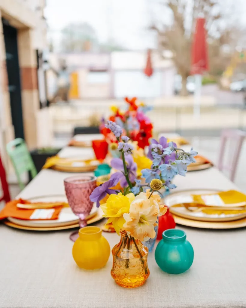 Décoration de table colorée pour un mariage de printemps avec fleurs vives et verrerie vibrante.