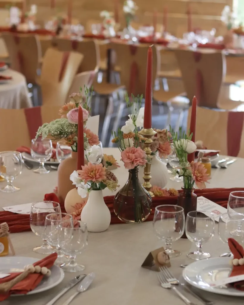 Centre de table avec vases et bougies issus d’une location-déco-mariage, dans une ambiance terracotta et crème. Les erreurs à éviter location déco mariage