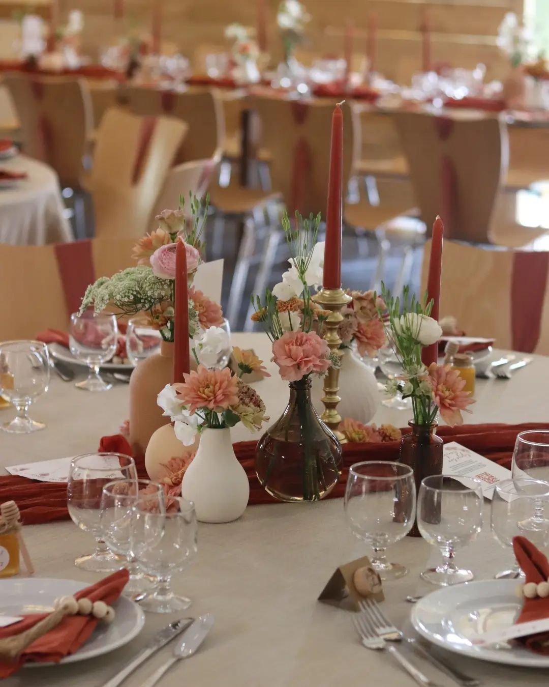 Centre de table avec vases et bougies issus d’une location-déco-mariage, dans une ambiance terracotta et crème. Les erreurs à éviter location déco mariage