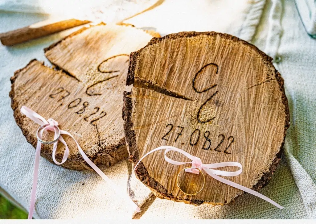 Porte-alliances en rondins de bois gravés, revisités pour un mariage champêtre moderne.