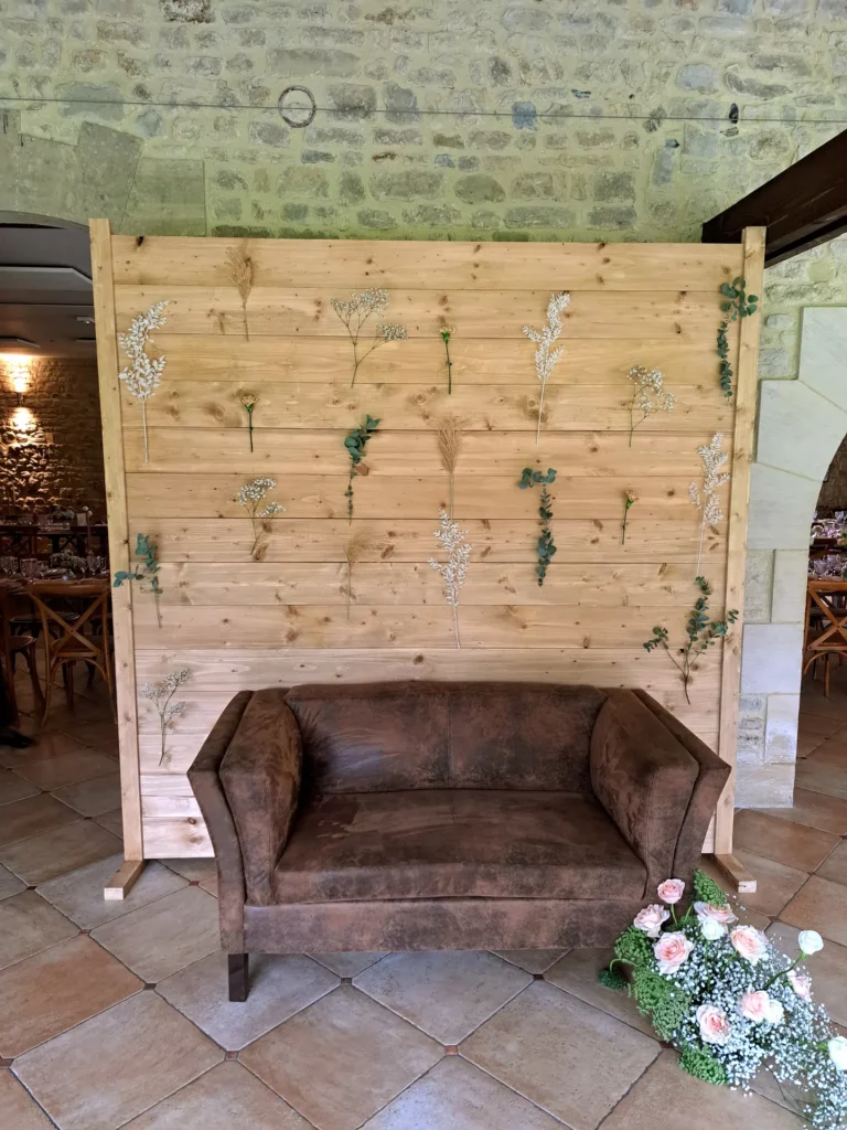 Canapé Victorien en suédine patiné placé devant une grande structure en bois ornée de fleurs séchées, installé en intérieur