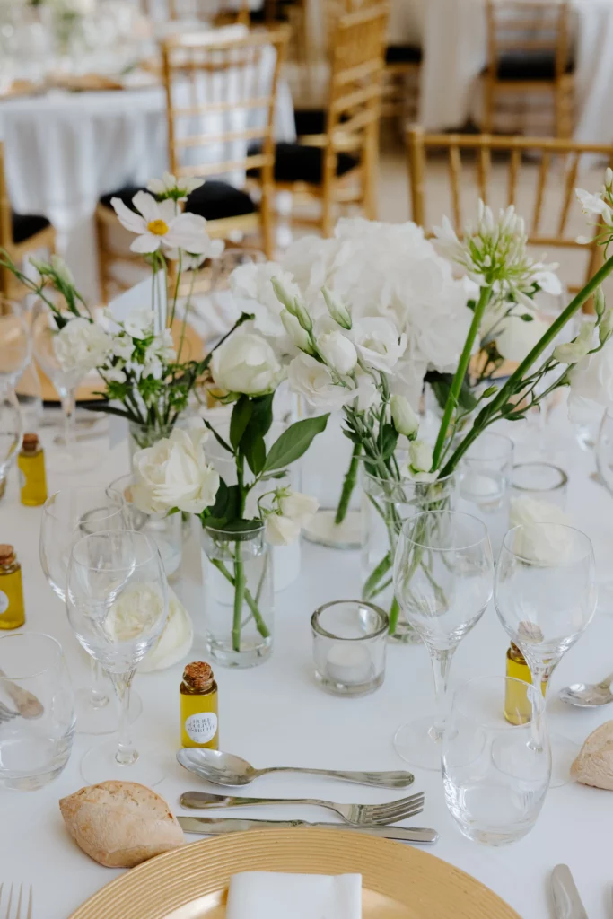 Centre de table avec vases assortis, fleurs blanches par O2rose et fiole d’huile d’olive à la truffe dorée, un exemple d’élément décoratif qui compte dans le budget décoration mariage