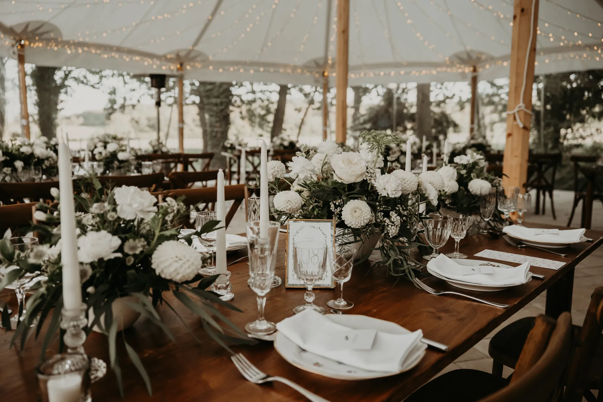 Décoration de mariage élégante sous tente en Normandie, avec compositions florales blanches, bougies fines et art de la table raffiné, illustrant les bonnes pratiques évoquées dans l’article « 7 erreurs à éviter en décoration de mariage ».