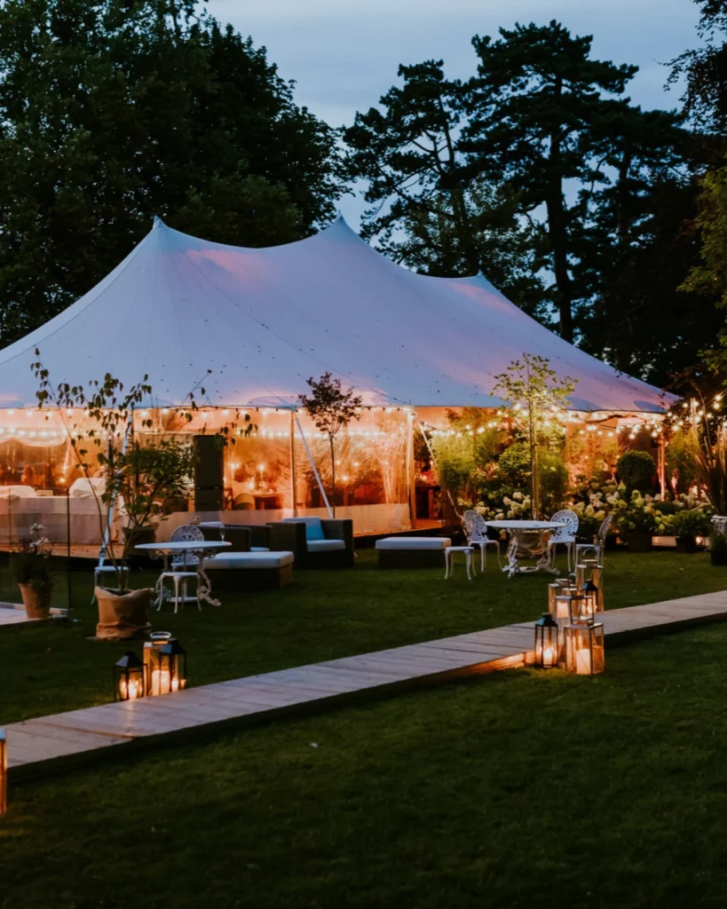 Tente illuminée au Château de Chènevière à Bayeux, avec lanternes et guirlandes créant une lumière mariage chaleureuse pour une réception en soirée. Photo Nicolas Desvages.