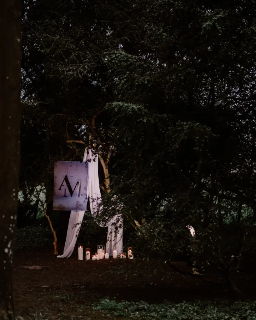 Décoration nocturne au Château des Requêtes avec voilage blanc et bougies créant une lumière mariage douce et mystérieuse sous les arbres. Photo De l’Ombre à la Lumière.