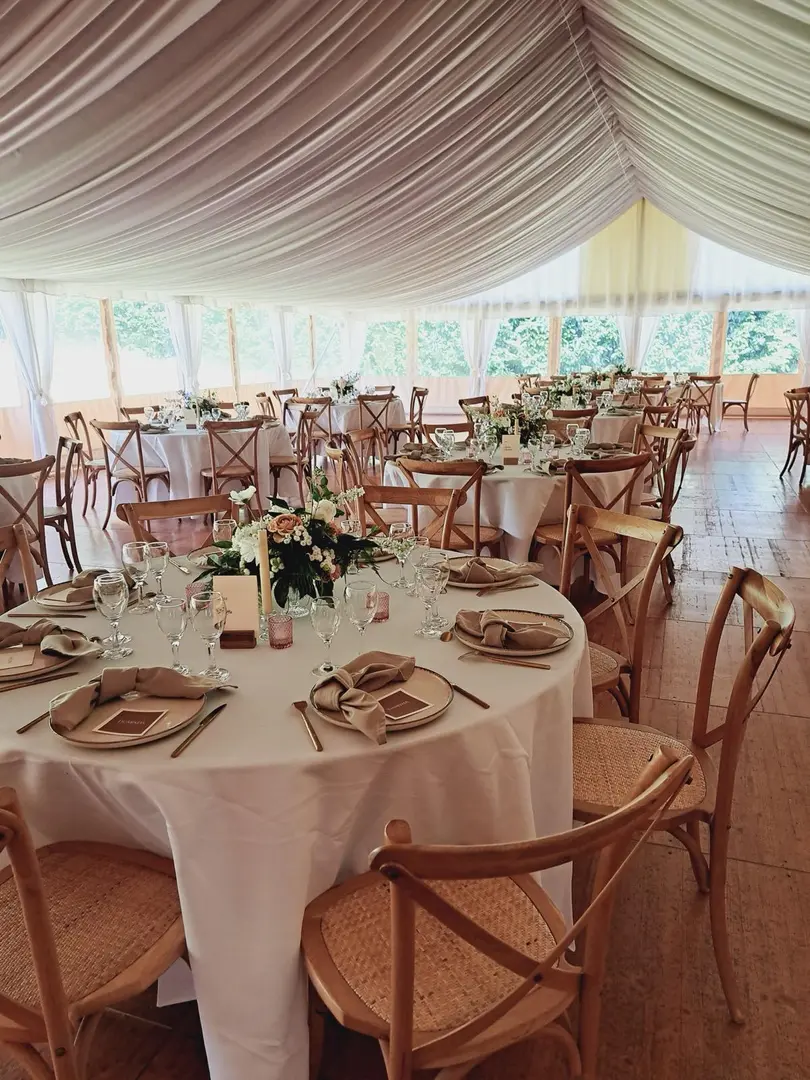 Décoration complète d’une réception de mariage sous tente avec tables dressées, fleurs et mobilier en Normandie