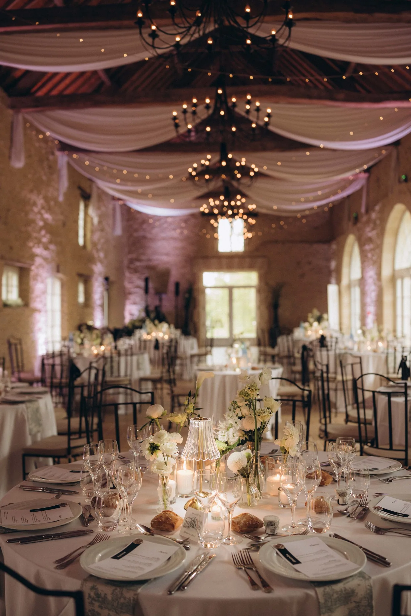 Décoration de salle de mariage avec tables rondes, bougies et travail du plafond