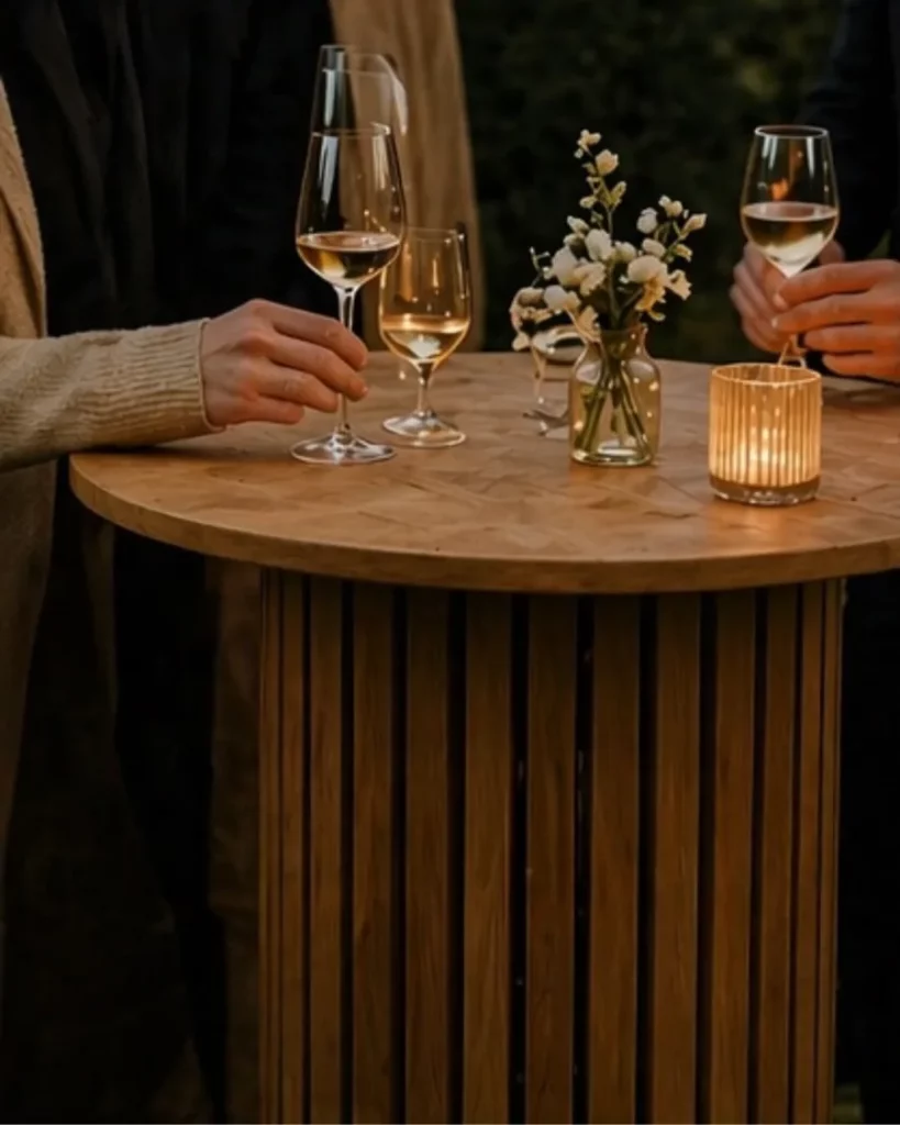 Mange-debout en bois pendant un cocktail de mariage avec verres et petite composition florale