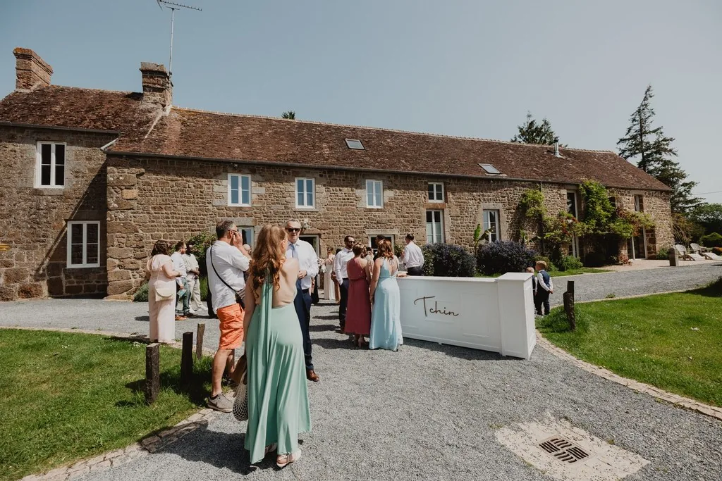 Invités réunis autour du bar pendant le vin d'honneur d'un mariage en extérieur