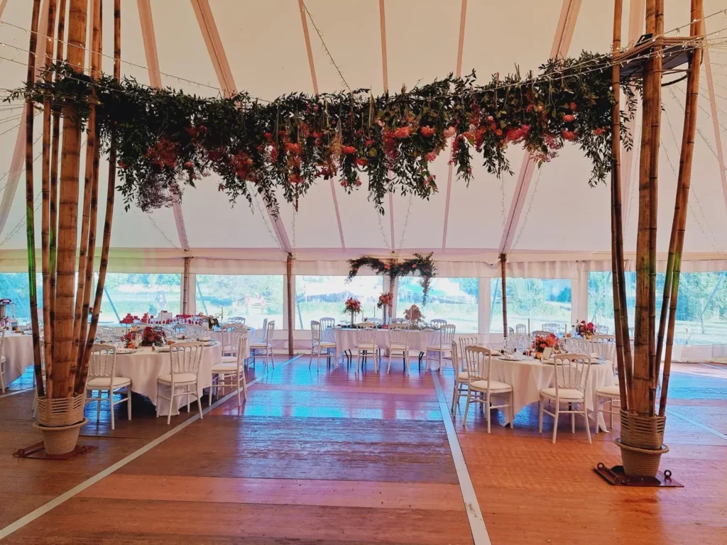 Chapiteau de mariage vu d'ensemble, piste de danse centrale, allées de circulation et tables rondes dressées On dessine d'abord les circulations et l'implantation des tables. La décoration arrive ensuite.
