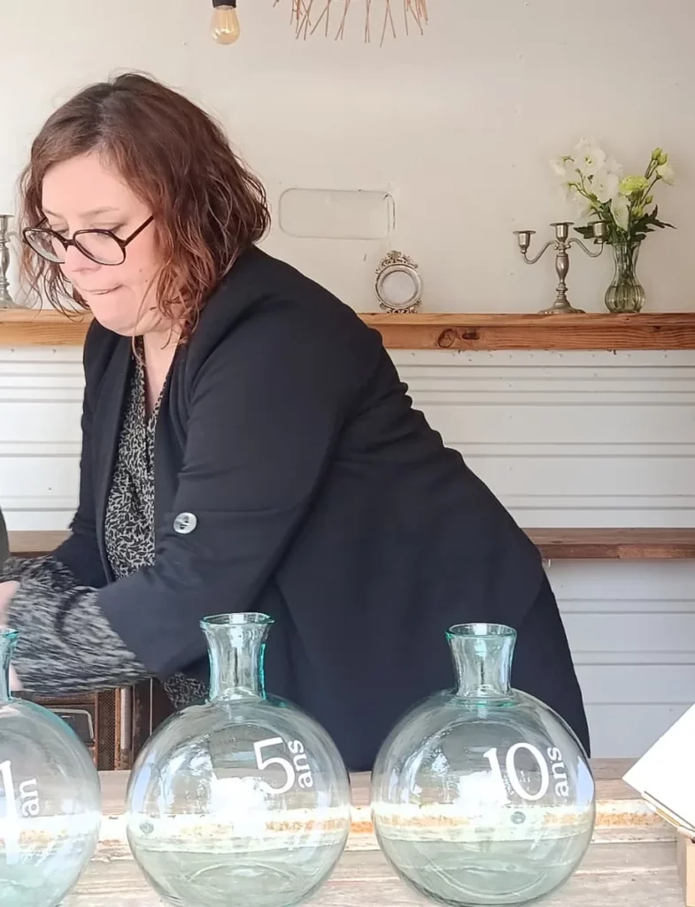 Marie Desaunay installant une décoration de mariage, dames-jeannes en verre dans un espace livre d'or au Manoir de Chivré (prouvant que l'intelligence artificielle IA ne peut pas installer la décoration de mariage)