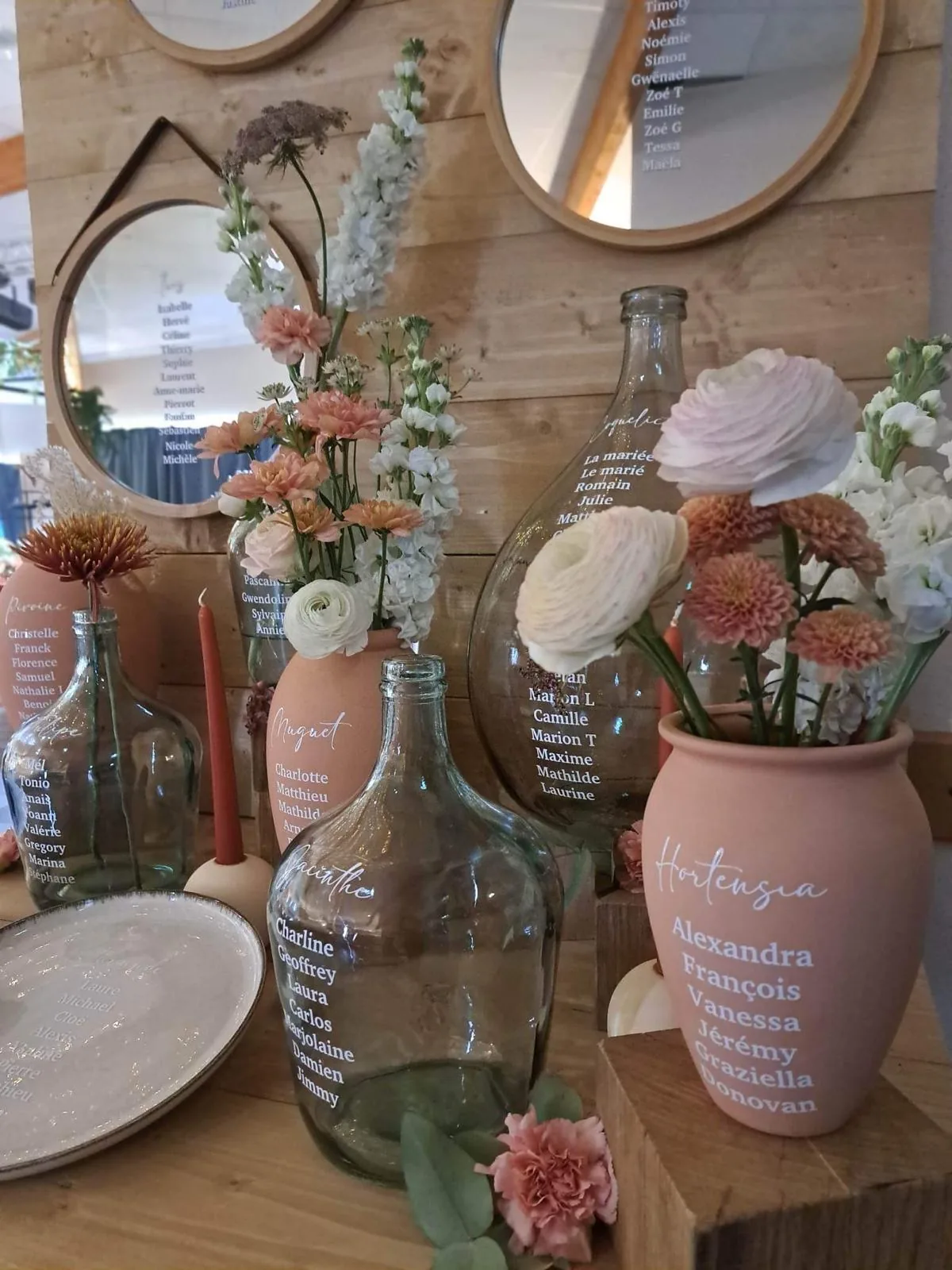 Plan de table mariage avec prénoms des invités sur des bouteilles en verre