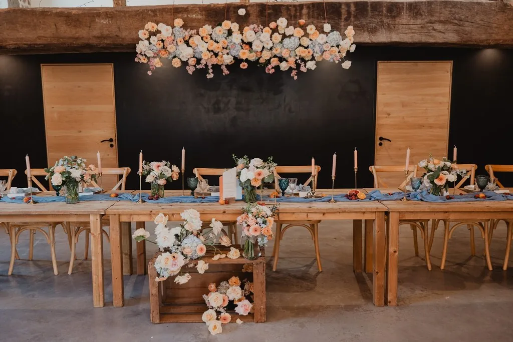 Table d'honneur de mariage et suspension florale dans une grange de réception en Normandie