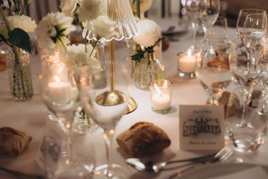 Table de mariage dressée aux chandelles avec fleurs blanches, verres en cristal et bois sombre Trois éléments répétés d'un bout à l'autre de la table. C'est ce que produit une direction tenue.