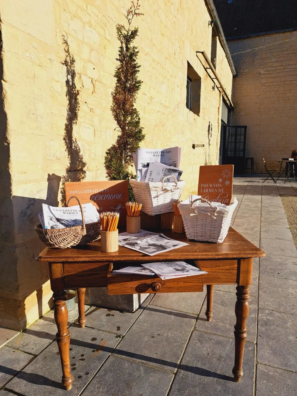 décoration de mariage : Table d'attente avec gazettes des mariés, crayons et paniers avant la cérémonie, mariage au domaine de la Cour des Lys