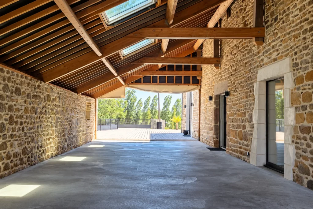 Photo prise lors d'une visite technique mariage - Espace de réception vide avec charpente en bois et murs en pierre, avant sa mise en décoration